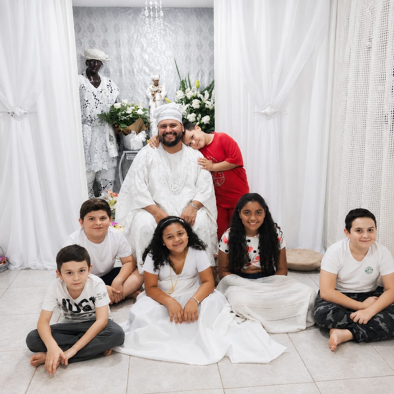 Babalorixá Bruno com crianças da casa diante do assentamento de Oxalá